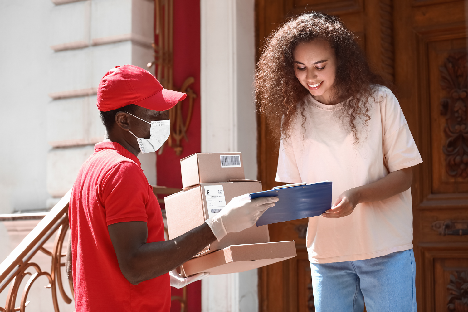 A young adult receiving a plain, discreet package from a delivery driver in front of a modern home.