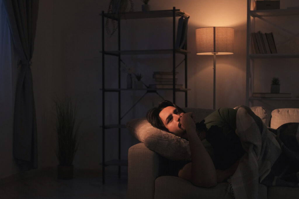 Man feeling mellow while lounging on couch with soft lighting